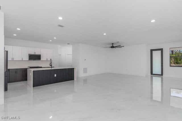 kitchen featuring marble finish floor, freestanding refrigerator, open floor plan, a kitchen island with sink, and white cabinets