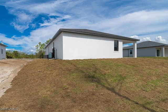 view of property exterior featuring central air condition unit, a lawn, and stucco siding