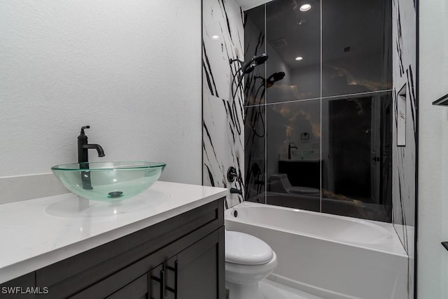 bathroom with toilet, a textured wall, bathing tub / shower combination, and vanity