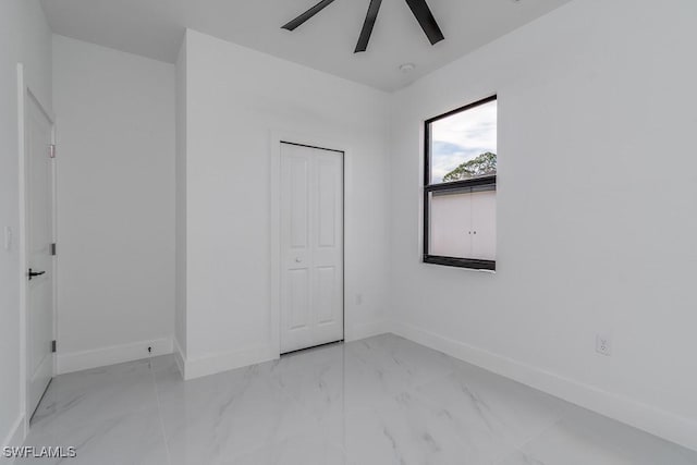 unfurnished bedroom with marble finish floor, baseboards, and a closet