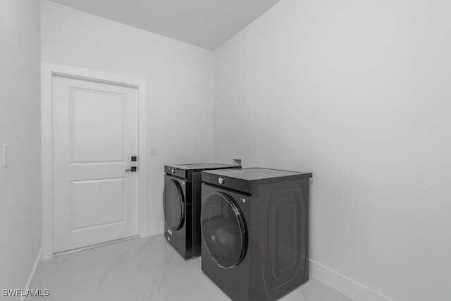 laundry area featuring laundry area, baseboards, marble finish floor, and separate washer and dryer