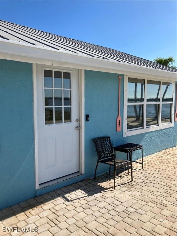 entrance to property with a standing seam roof, metal roof, and stucco siding