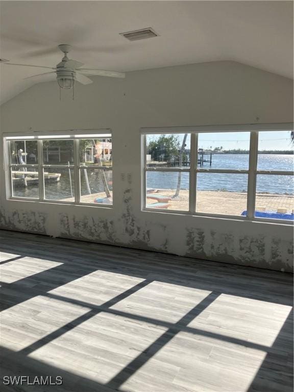 unfurnished sunroom with a water view, vaulted ceiling, visible vents, and ceiling fan