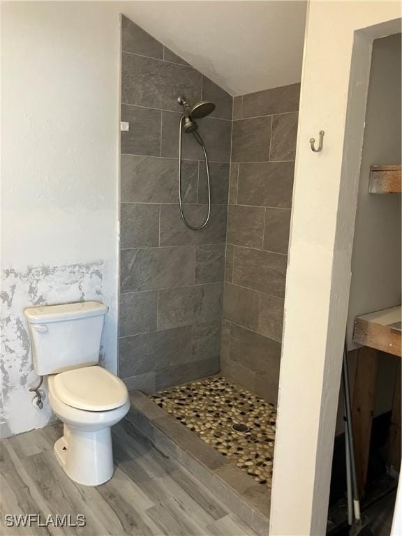 full bath featuring tiled shower, wood finished floors, and toilet