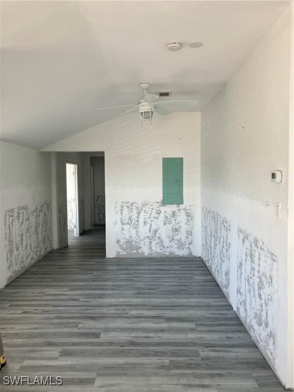 unfurnished room featuring a ceiling fan, lofted ceiling, visible vents, and wood finished floors