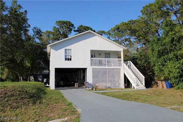 view of front facade featuring driveway, stairway, covered porch, a front lawn, and stucco siding