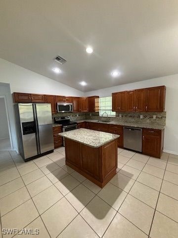 3510 5th St SW, Lehigh Acres, FL 33976 - kitchen with a center island, tasteful backsplash, visible vents, lofted ceiling, and appliances with stainless steel finishes