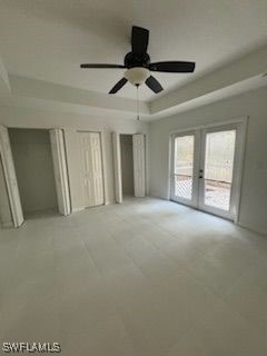 3510 5th St SW, Lehigh Acres, FL 33976 - unfurnished bedroom with multiple closets, ceiling fan, french doors, a tray ceiling, and access to exterior
