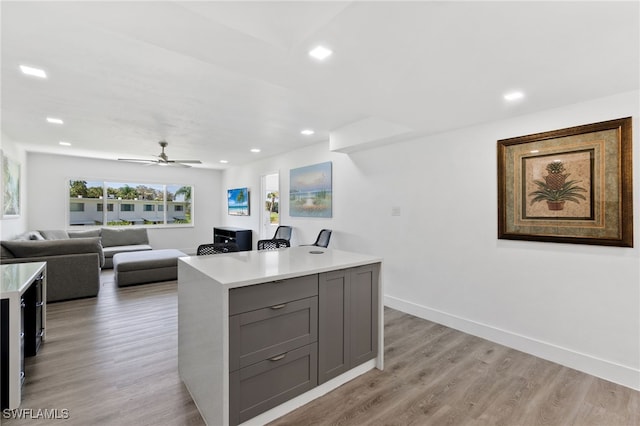 kitchen with light countertops, light wood finished floors, gray cabinets, and baseboards