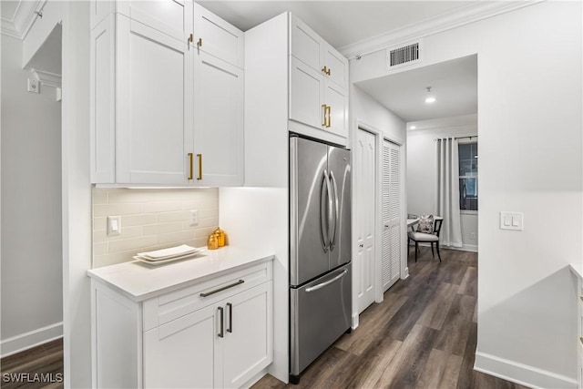 kitchen with light countertops, dark wood-style flooring, stainless steel fridge, and visible vents