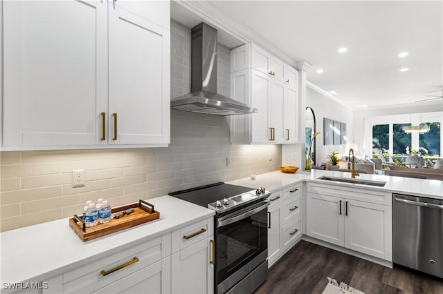 kitchen with tasteful backsplash, wall chimney exhaust hood, appliances with stainless steel finishes, light countertops, and a sink