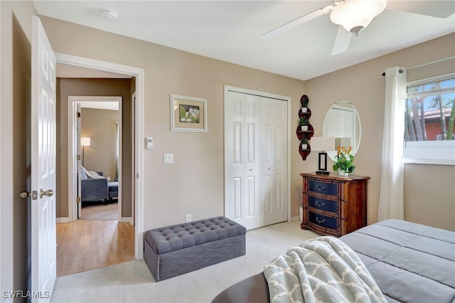 bedroom with ceiling fan, a closet, light carpet, and baseboards