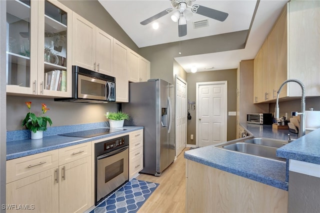 kitchen featuring stainless steel appliances, a sink, visible vents, light wood-style floors, and glass insert cabinets