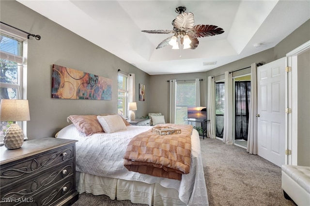 bedroom featuring visible vents, a raised ceiling, a ceiling fan, carpet, and access to outside