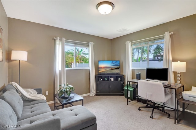 carpeted living area with visible vents, a wealth of natural light, and baseboards