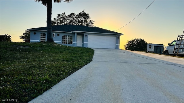 ranch-style house with stucco siding, driveway, an attached garage, and a lawn