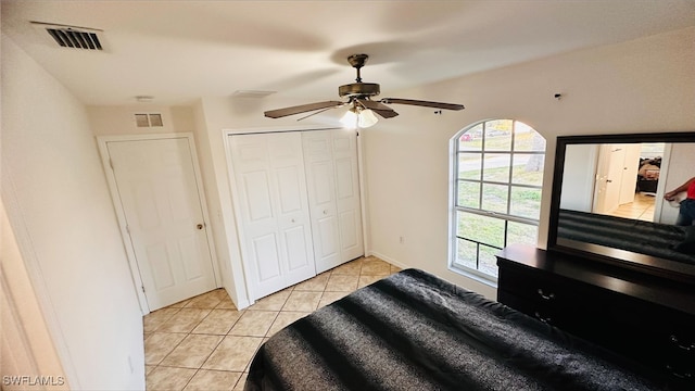 bedroom featuring light tile patterned floors, visible vents, a ceiling fan, and a closet