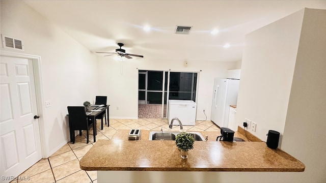 kitchen with light tile patterned floors, visible vents, freestanding refrigerator, and a sink