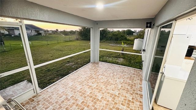 unfurnished sunroom featuring washer / dryer and a rural view