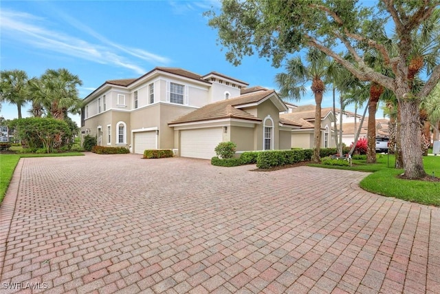 view of front of property featuring a tiled roof, decorative driveway, and stucco siding