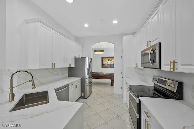 kitchen with appliances with stainless steel finishes, backsplash, a sink, and white cabinets