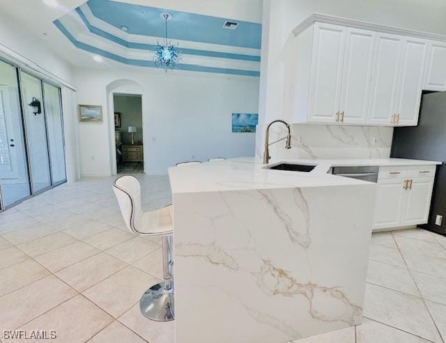 kitchen featuring arched walkways, white cabinetry, a sink, and light tile patterned floors