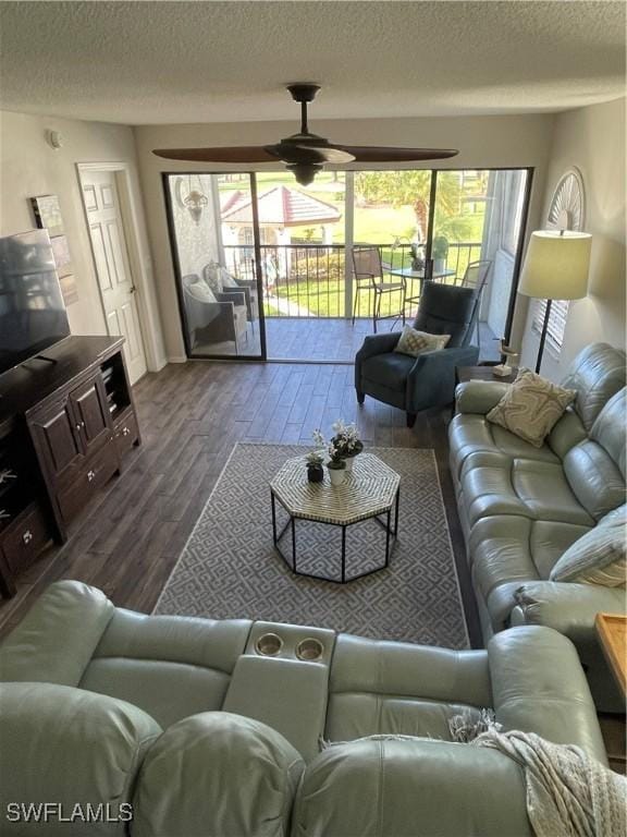 living room with ceiling fan, a textured ceiling, and dark wood-style flooring