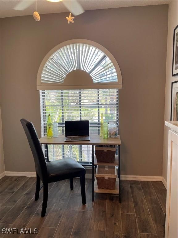 office space featuring baseboards, a healthy amount of sunlight, lofted ceiling, and wood tiled floor