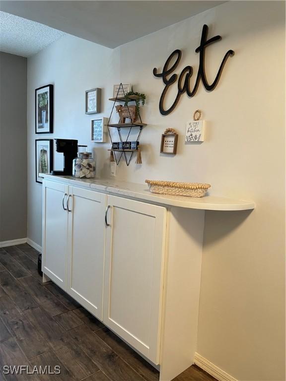 bar with dark wood-style flooring and baseboards