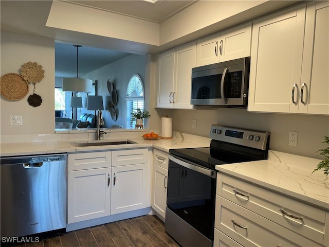 kitchen featuring stainless steel appliances, a sink, white cabinets, and wood tiled floor