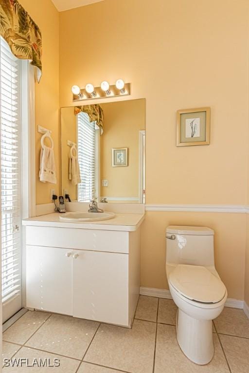2109 Morning Sun Ln, Naples, FL 34119 - bathroom featuring tile patterned floors, toilet, vanity, and a healthy amount of sunlight
