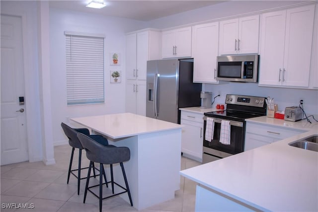 kitchen featuring stainless steel appliances, a kitchen island, white cabinets, and a kitchen breakfast bar