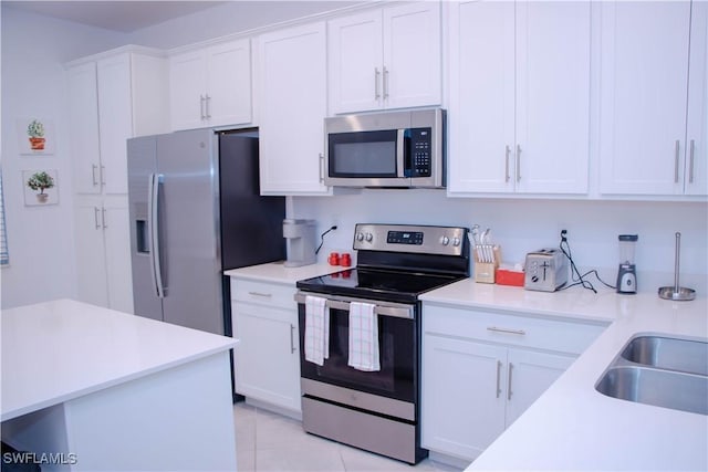 kitchen featuring light countertops, appliances with stainless steel finishes, white cabinets, a sink, and light tile patterned flooring