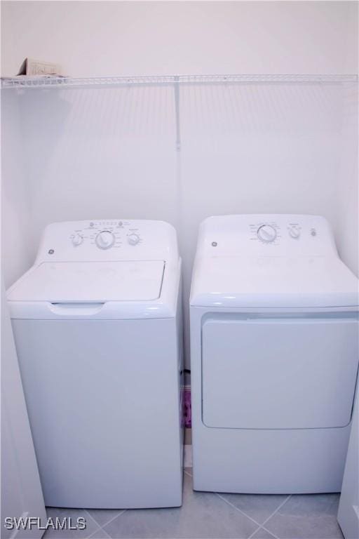 washroom with laundry area, washer and clothes dryer, and light tile patterned floors