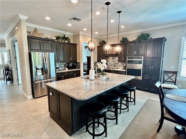 kitchen featuring stainless steel appliances, a large island, visible vents, and light stone counters