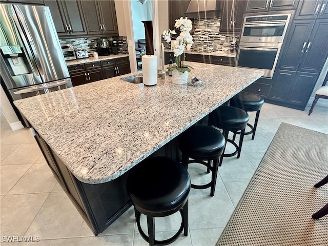 kitchen with appliances with stainless steel finishes, decorative backsplash, and light stone countertops