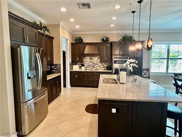 kitchen featuring visible vents, an island with sink, stainless steel appliances, a kitchen bar, and a sink