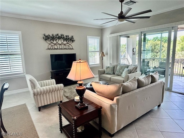 living room with light tile patterned floors, visible vents, ornamental molding, ceiling fan, and baseboards