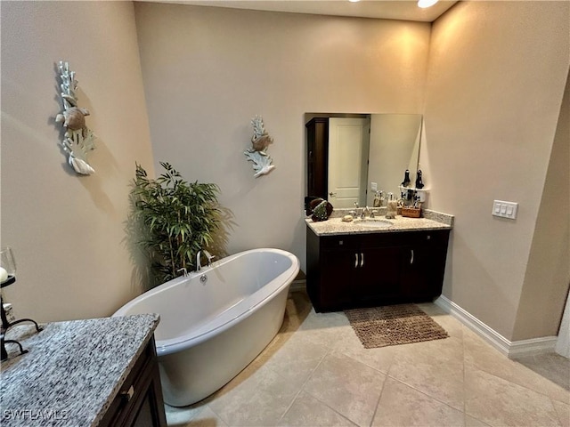 full bath featuring a freestanding bath, vanity, baseboards, and tile patterned floors