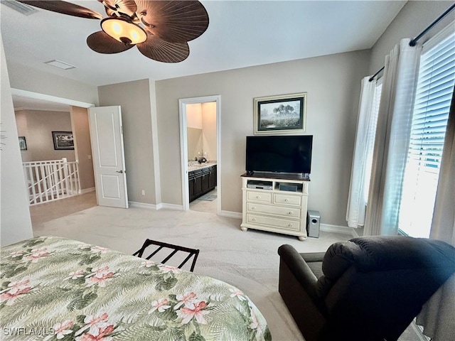 bedroom featuring a ceiling fan, light colored carpet, ensuite bath, and baseboards