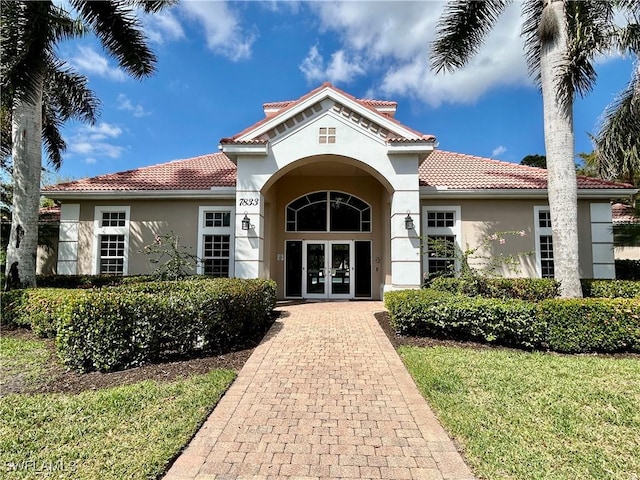 property entrance with french doors, a tile roof, and stucco siding