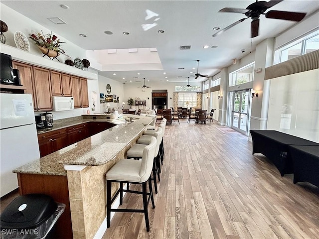 kitchen with stone counters, white appliances, visible vents, open floor plan, and light wood finished floors