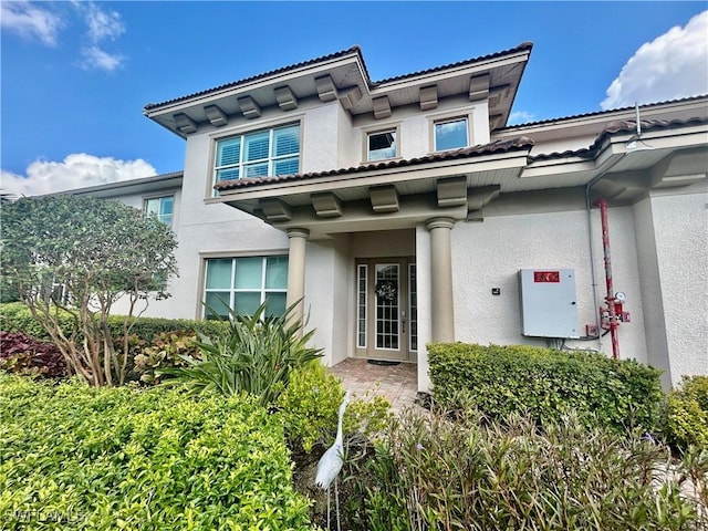 entrance to property with a tiled roof and stucco siding