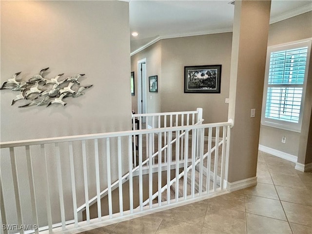 corridor with ornamental molding, tile patterned flooring, baseboards, and an upstairs landing