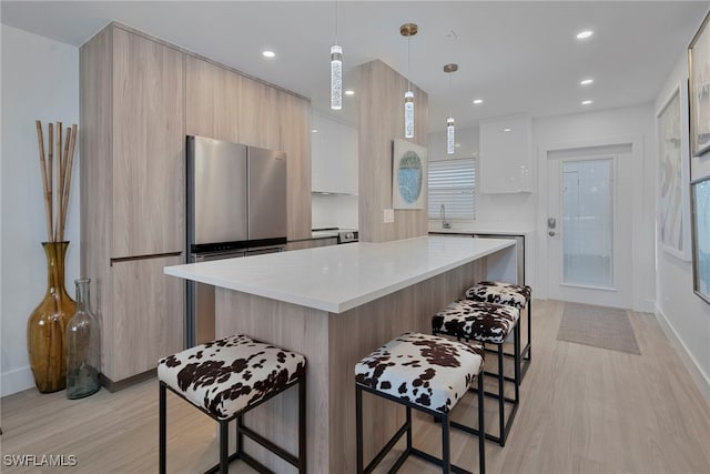 kitchen with a breakfast bar, modern cabinets, freestanding refrigerator, and a center island