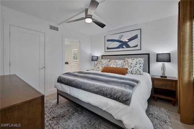 bedroom featuring light wood-type flooring, ensuite bath, visible vents, and a ceiling fan