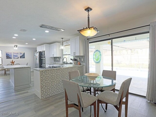 dining area with light wood-type flooring, visible vents, and recessed lighting