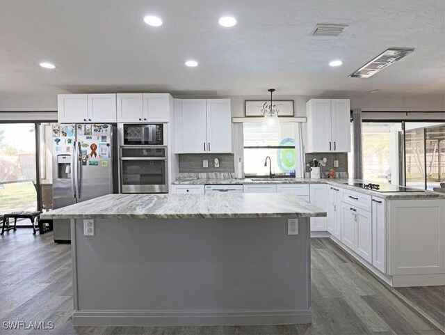 kitchen with stainless steel appliances, white cabinetry, a sink, and a kitchen island