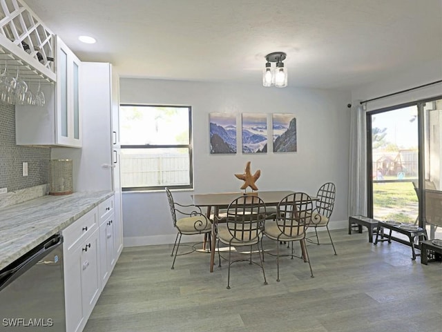 dining area with light wood-type flooring, a healthy amount of sunlight, baseboards, and recessed lighting