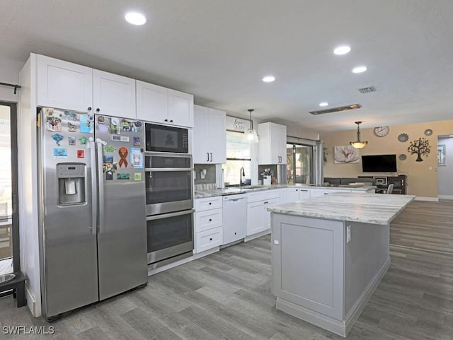 kitchen featuring appliances with stainless steel finishes, white cabinets, a peninsula, and wood finished floors